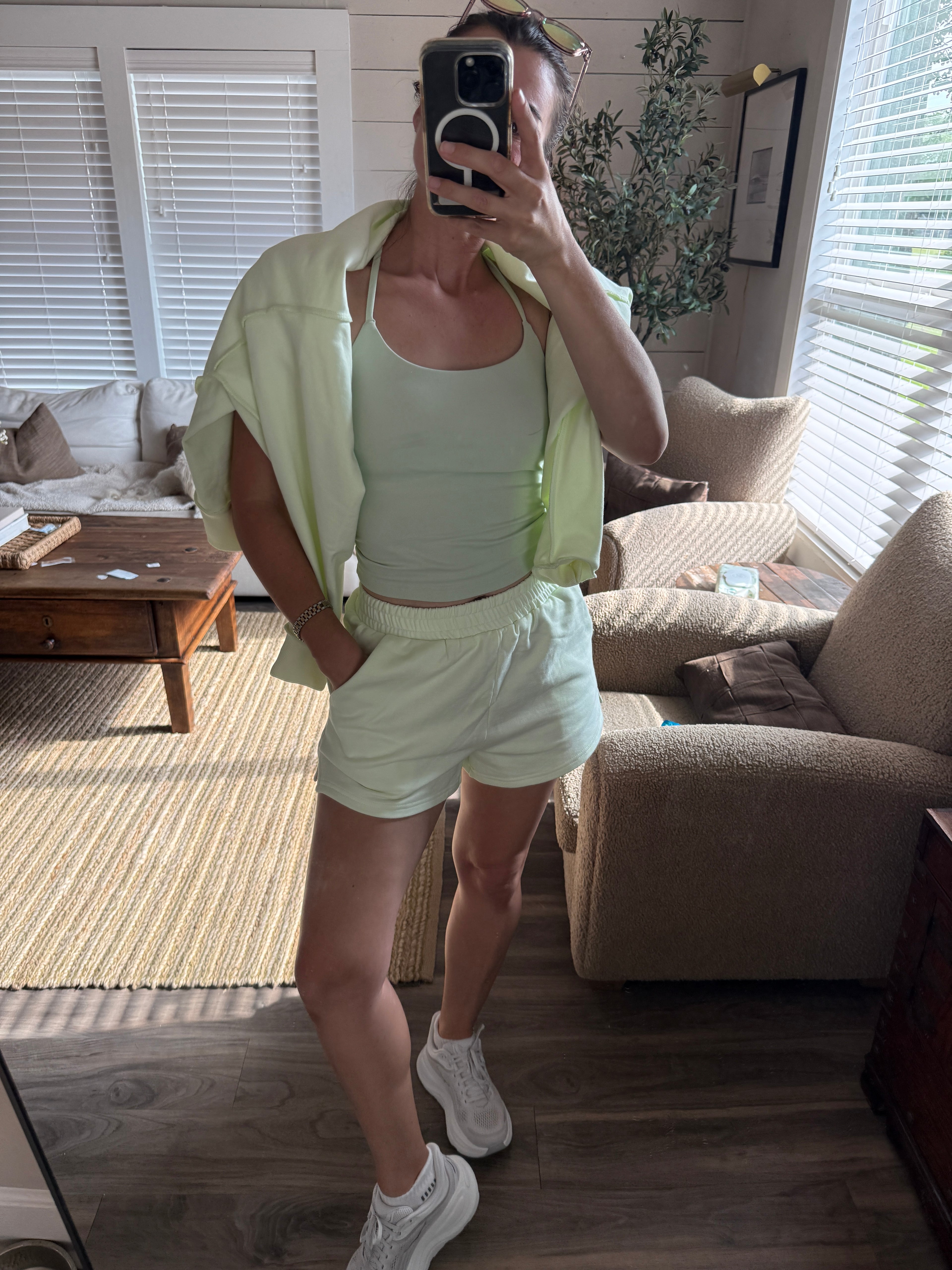 Person taking a mirror selfie in a living room wearing a light green outfit.