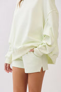 Light green oversized sweatshirt and shorts set on a plain background