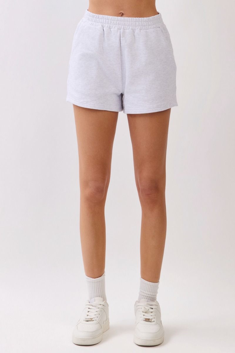 Person wearing light gray shorts on a white background