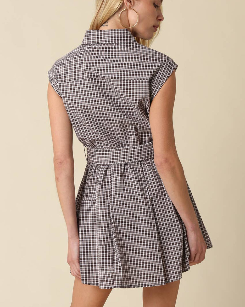Woman wearing a checkered dress against a beige background
