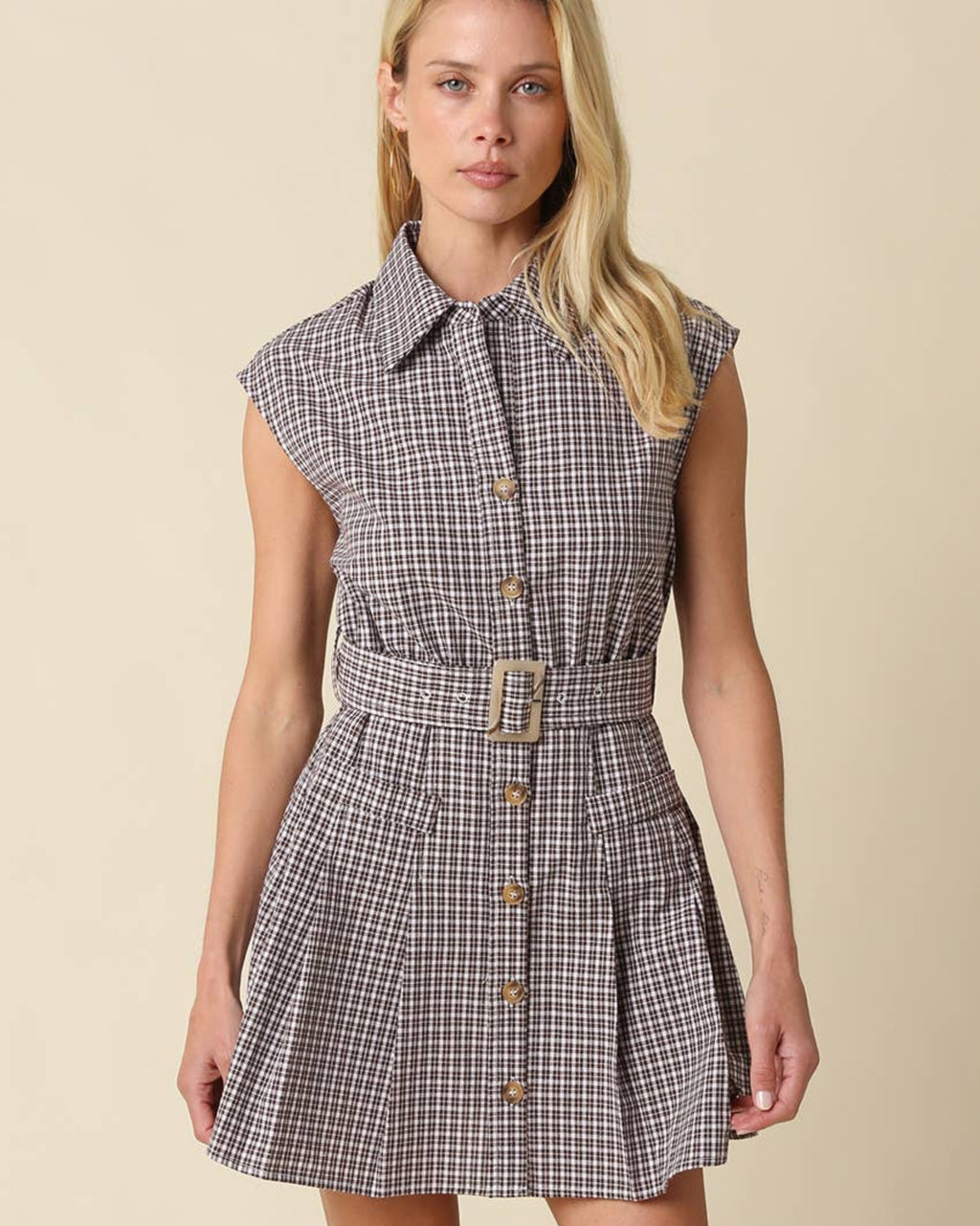 Woman wearing a plaid dress with a belt on a beige background