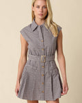 Woman wearing a plaid dress with a belt on a beige background